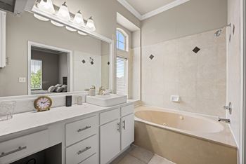 A bathroom with a tub, sink, and mirror.